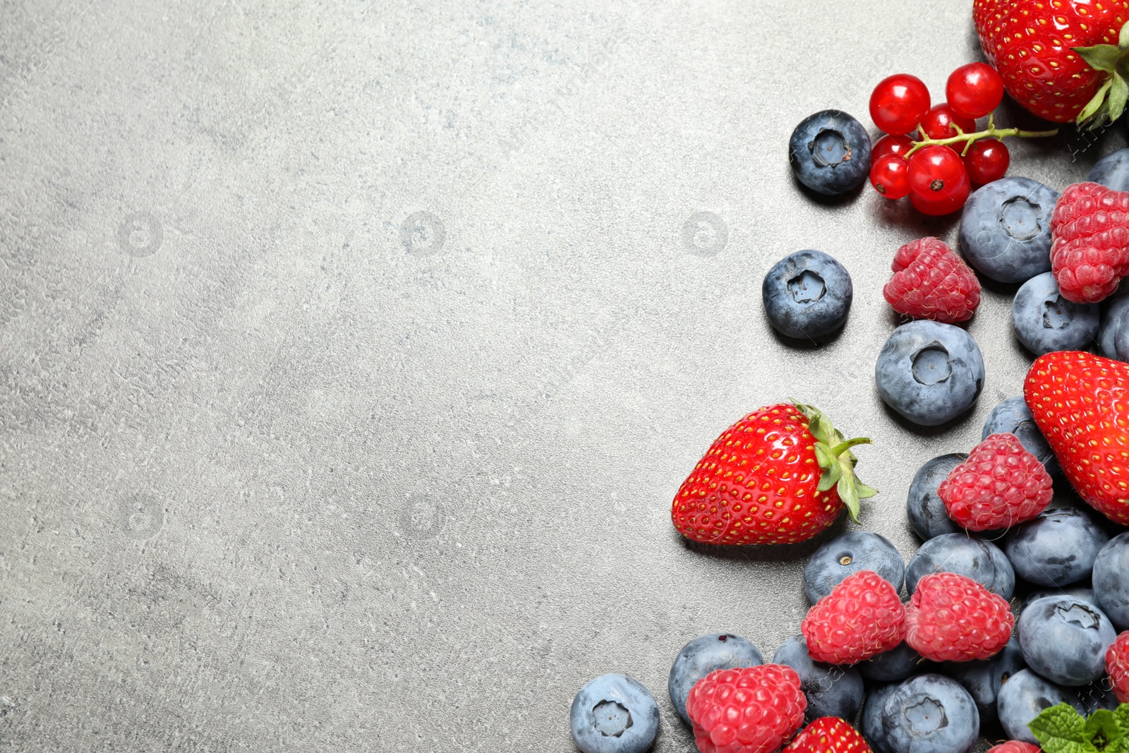 Photo of Different fresh berries on grey background, flat lay. Space for text