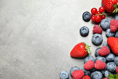 Photo of Different fresh berries on grey background, flat lay. Space for text