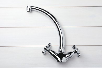 Photo of Double handle water tap on white wooden table, top view