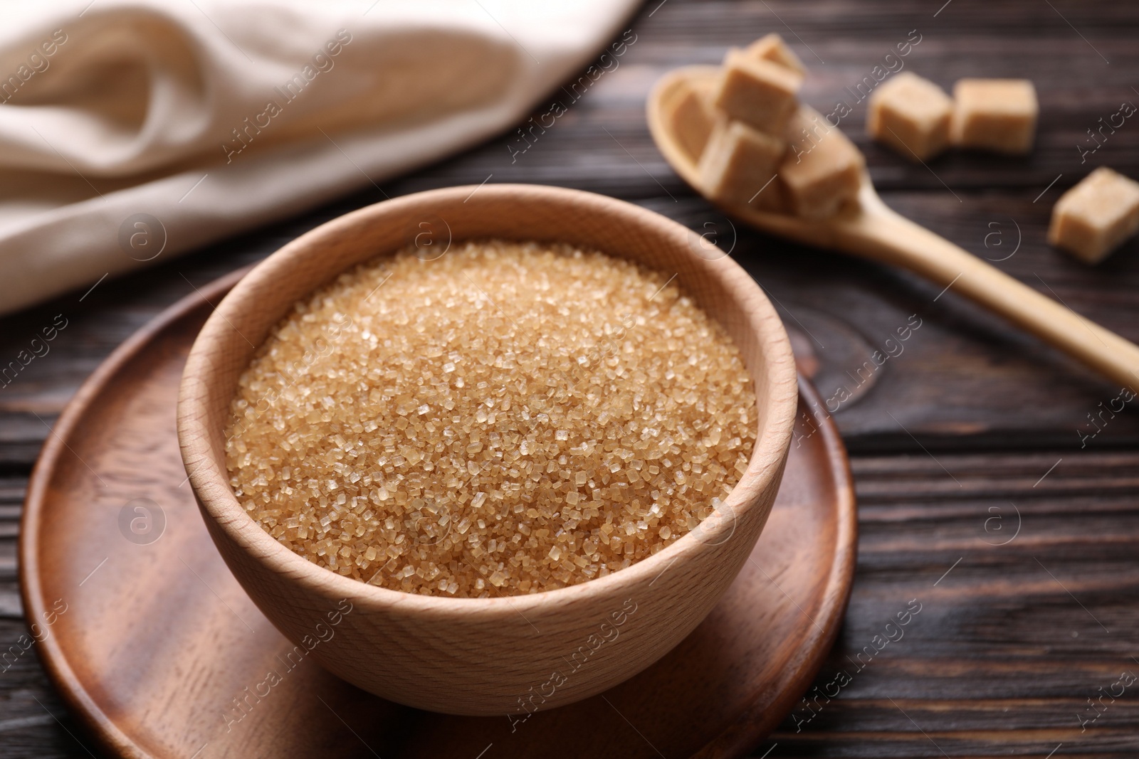 Photo of Brown sugar in bowl on wooden table, closeup