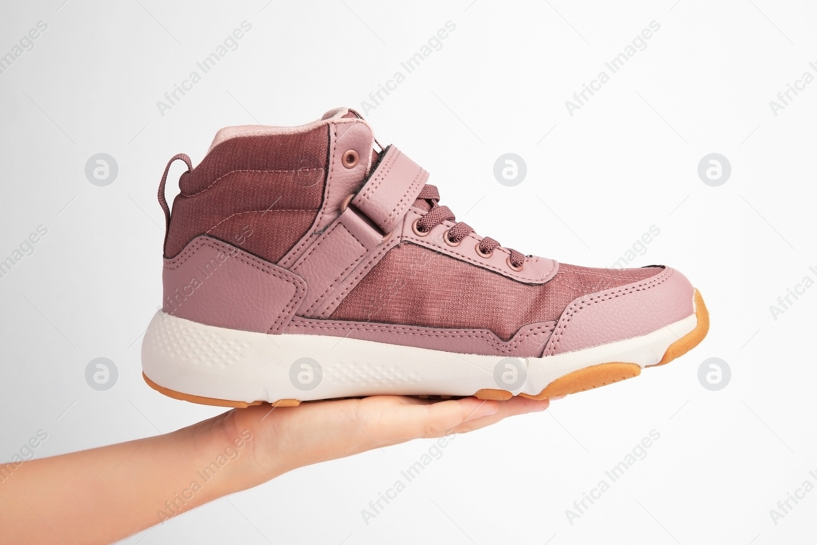 Photo of Girl holding stylish sneaker on white background, closeup