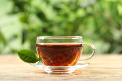 Cup of black tea on wooden table against blurred background. Space for text