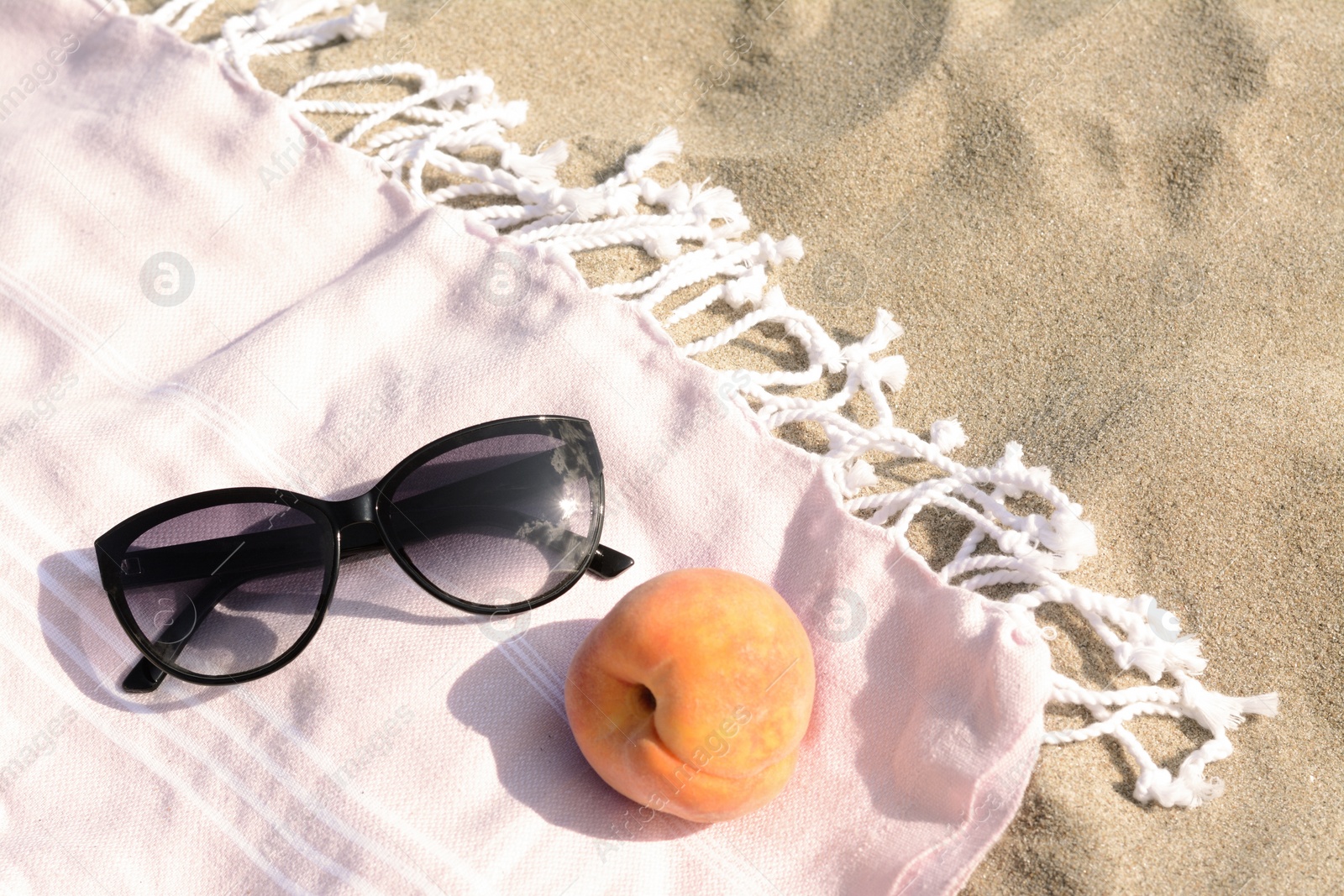 Photo of Beautiful sunglasses and peach on blanket, above view. Space for text