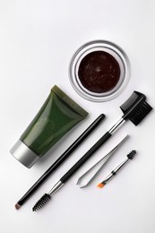 Photo of Flat lay composition with eyebrow henna, professional tools and cosmetic product on white background