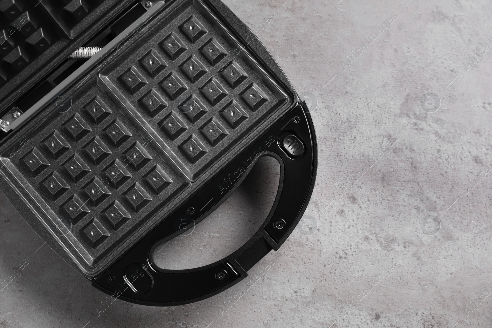 Photo of Modern waffle iron on grey stone table, top view