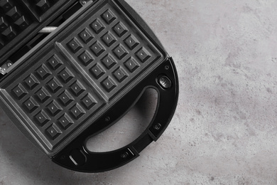 Photo of Modern waffle iron on grey stone table, top view