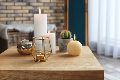 Photo of Burning candles on table indoors. Interior decor element