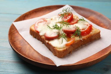 Photo of Tasty pizza toast with cheese, tomato and dill on light blue wooden table, closeup