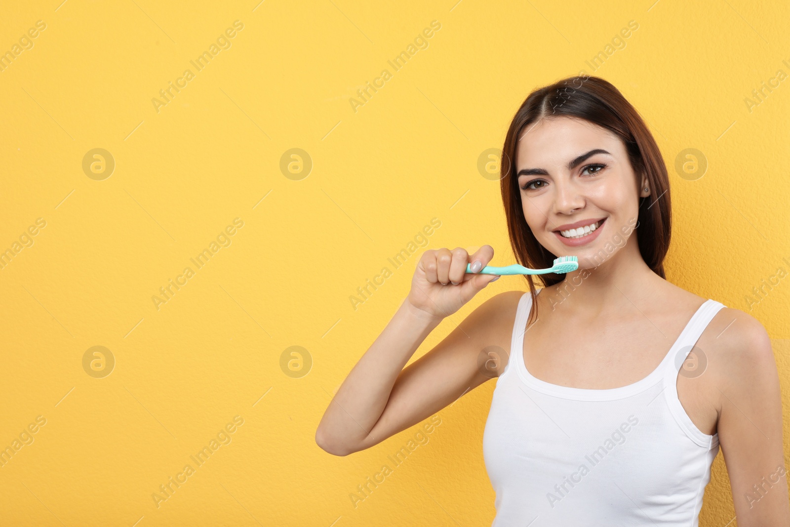 Photo of Beautiful woman brushing teeth on color background. Space for text