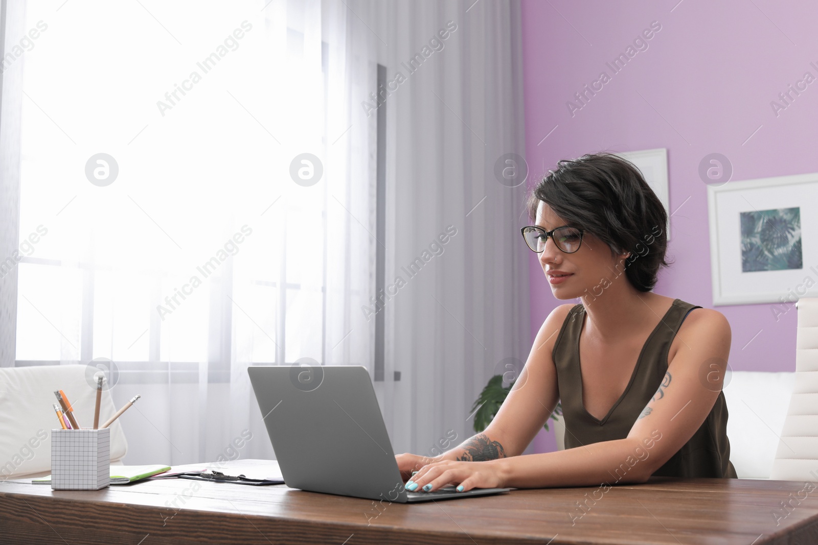 Photo of Young woman with modern laptop at desk in home office