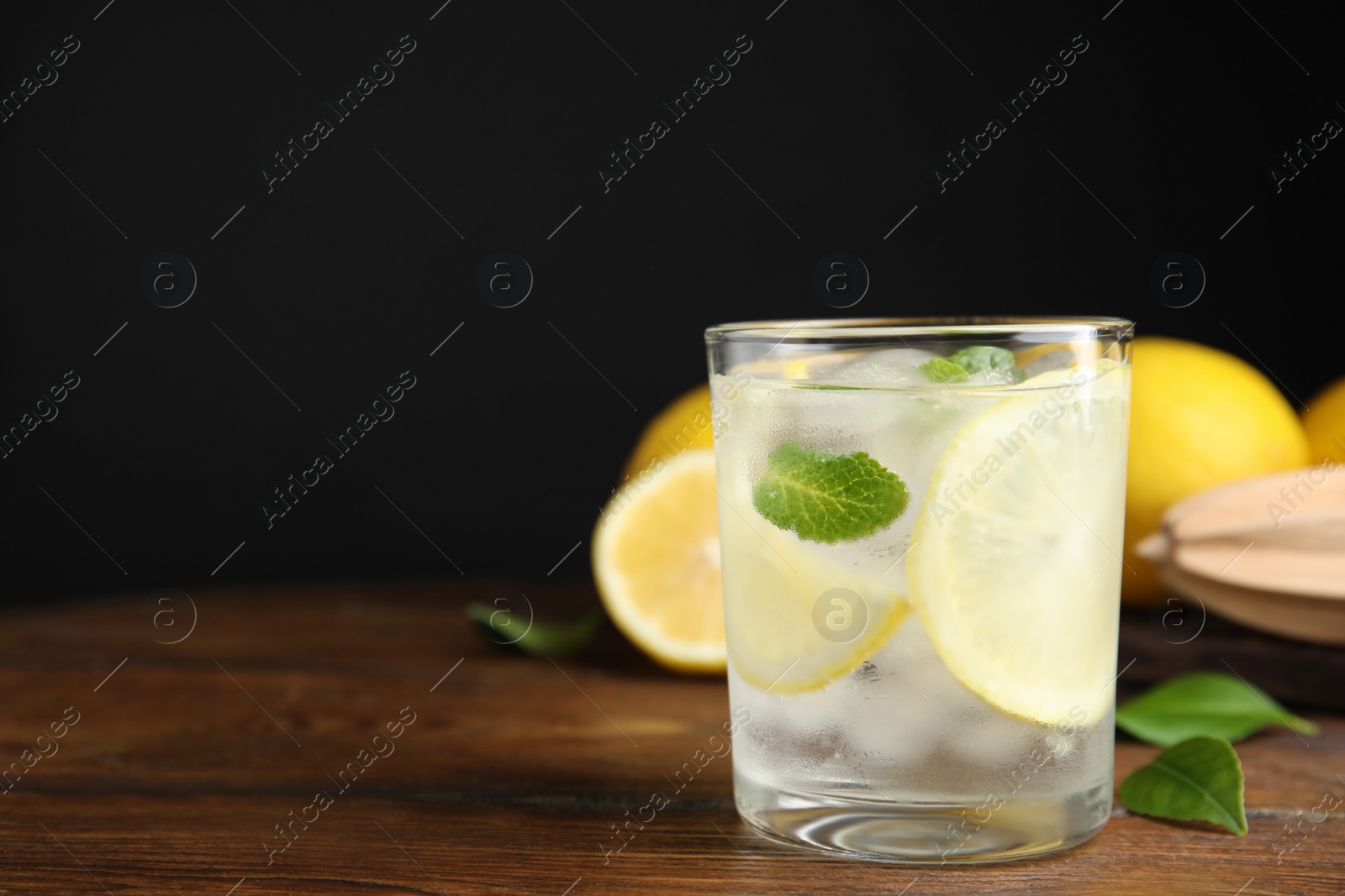 Photo of Cool freshly made lemonade in glass on wooden table. Space  for text