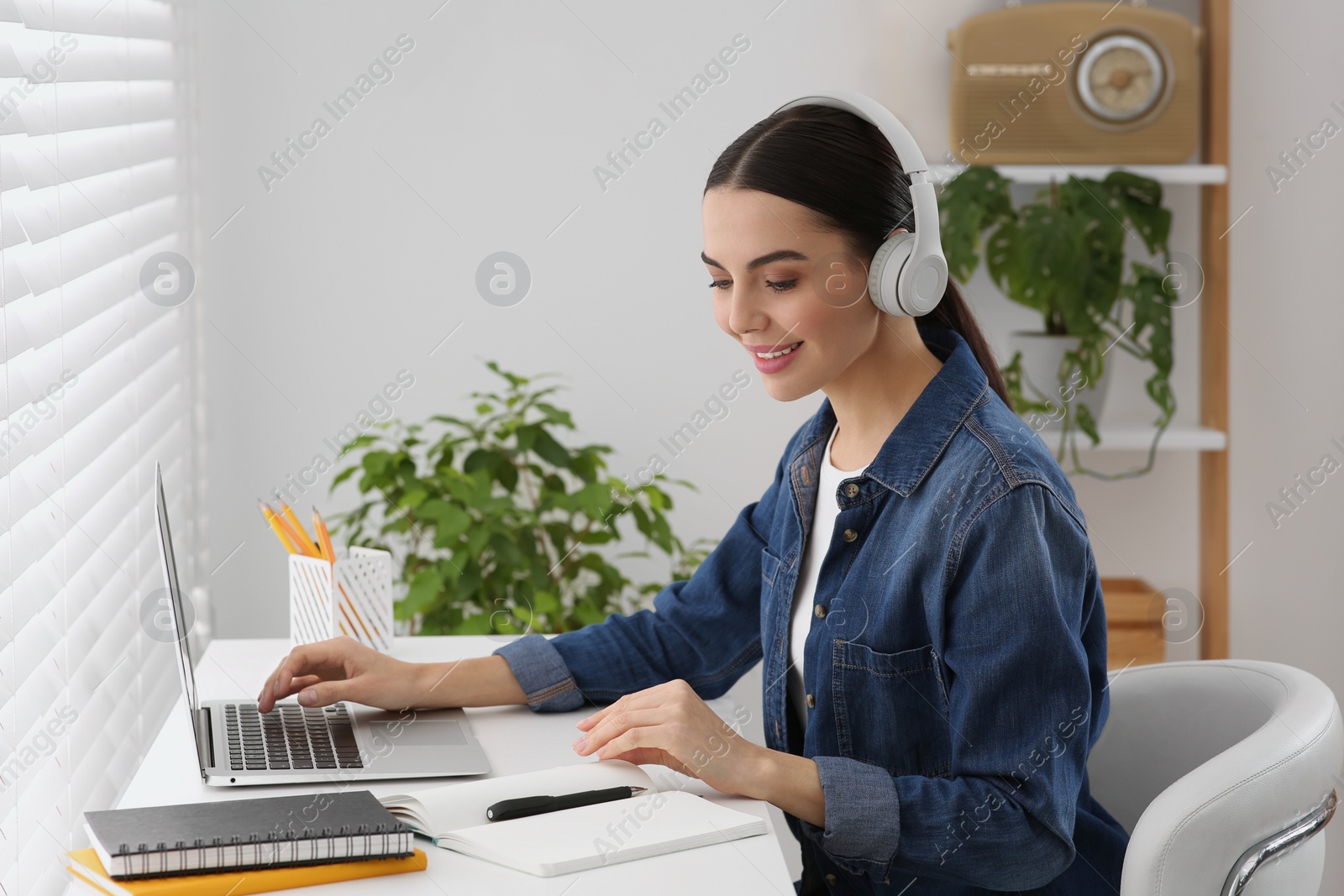 Photo of Woman in headphones studying on laptop at home. Online translation course