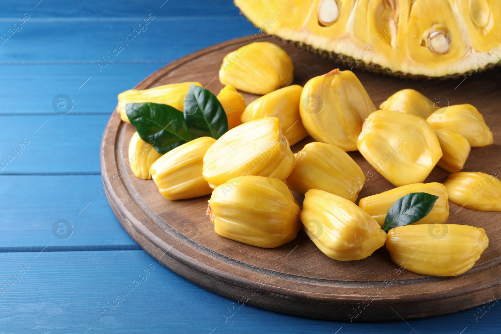 Photo of Delicious exotic jackfruit bulbs on blue wooden table