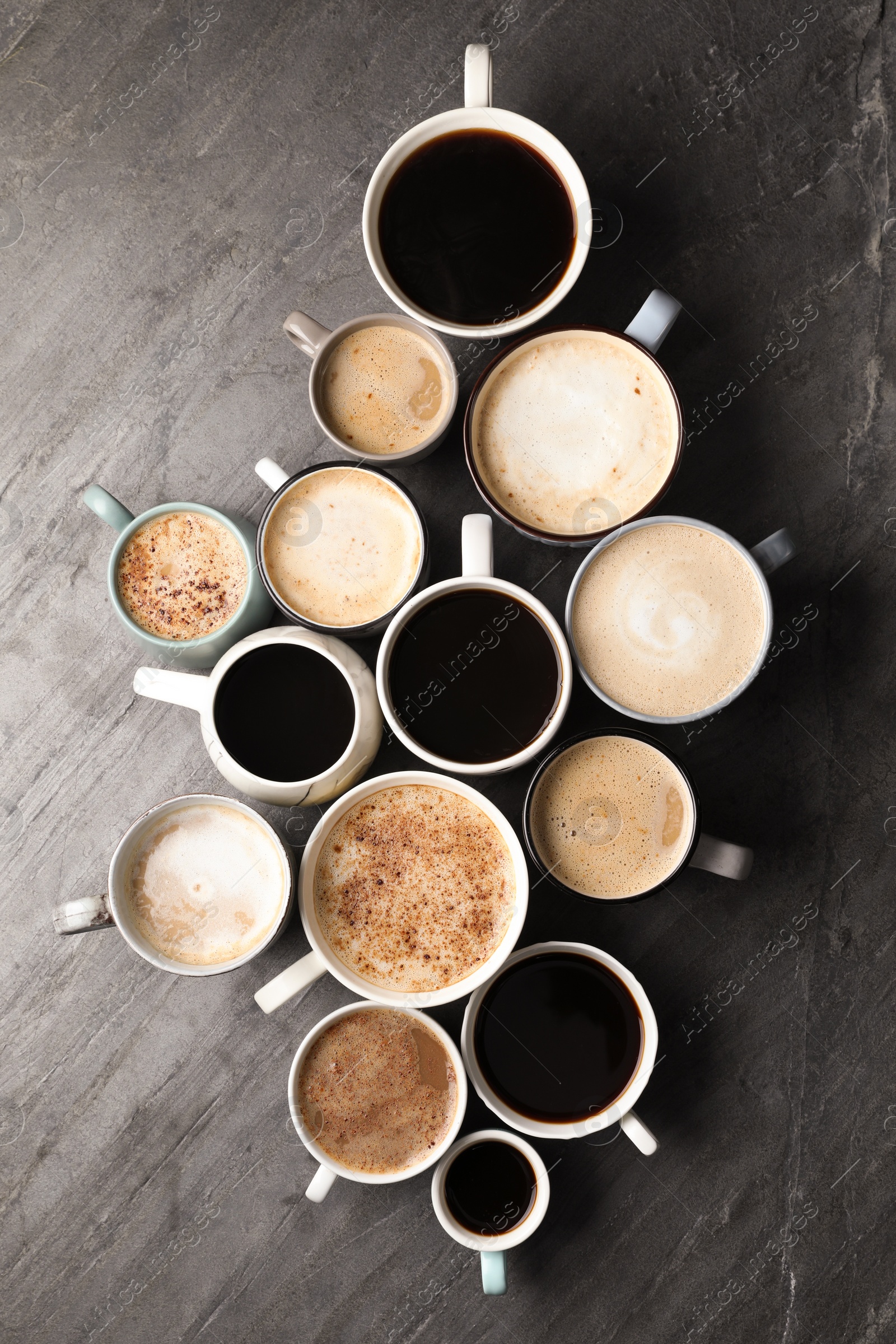 Photo of Many cups of different coffees on slate table, flat lay