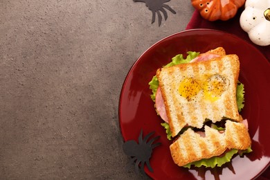 Photo of Cute monster sandwich with fried eggs on grey textured table, flat lay and space for text. Halloween snack