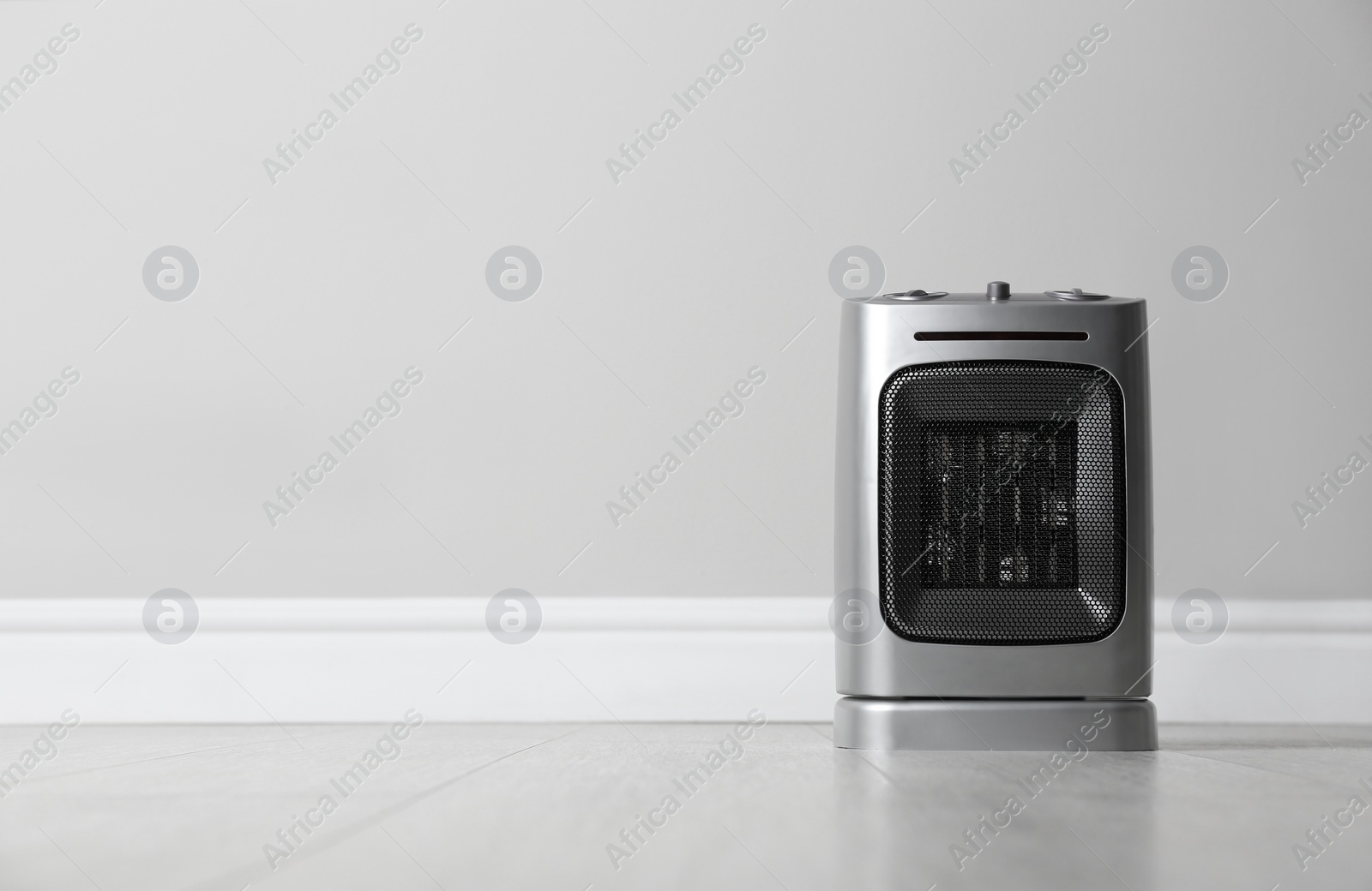 Photo of Modern electric fan heater on floor in room, space for text