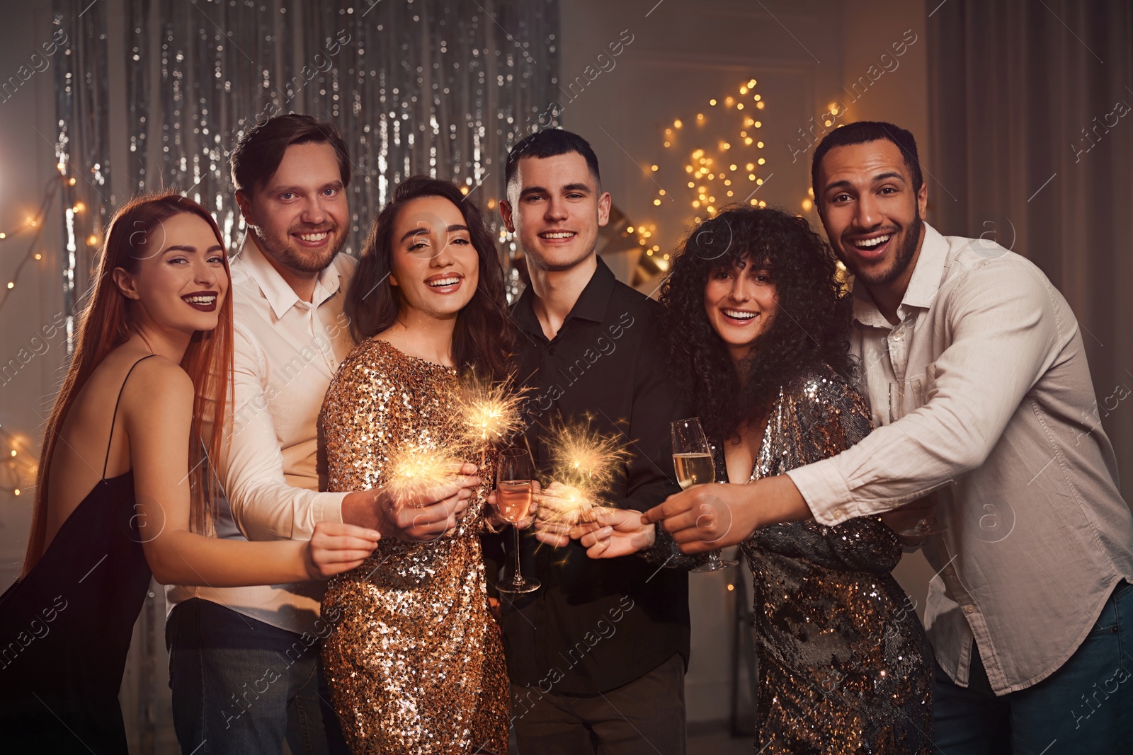 Photo of Happy friends with glasses of wine and sparklers celebrating birthday indoors