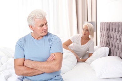 Photo of Mature couple with relationship problems ignoring each other in bedroom