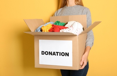 Woman holding box with donations on color background