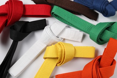 Photo of Colorful karate belts on white background, flat lay