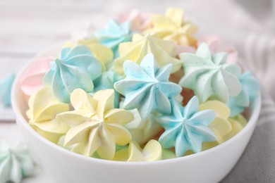 Photo of Tasty meringue cookies in bowl on white wooden table, closeup