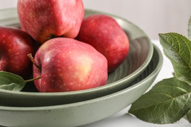Photo of Fresh red apples and leaves on white table, closeup