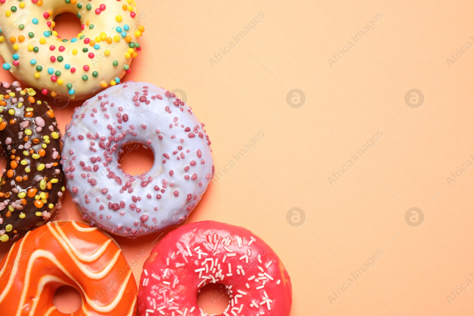 Photo of Delicious glazed donuts on orange background, flat lay. Space for text