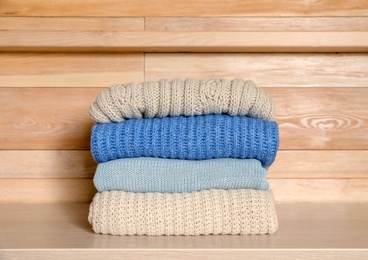 Photo of Stack of winter clothes against wooden background