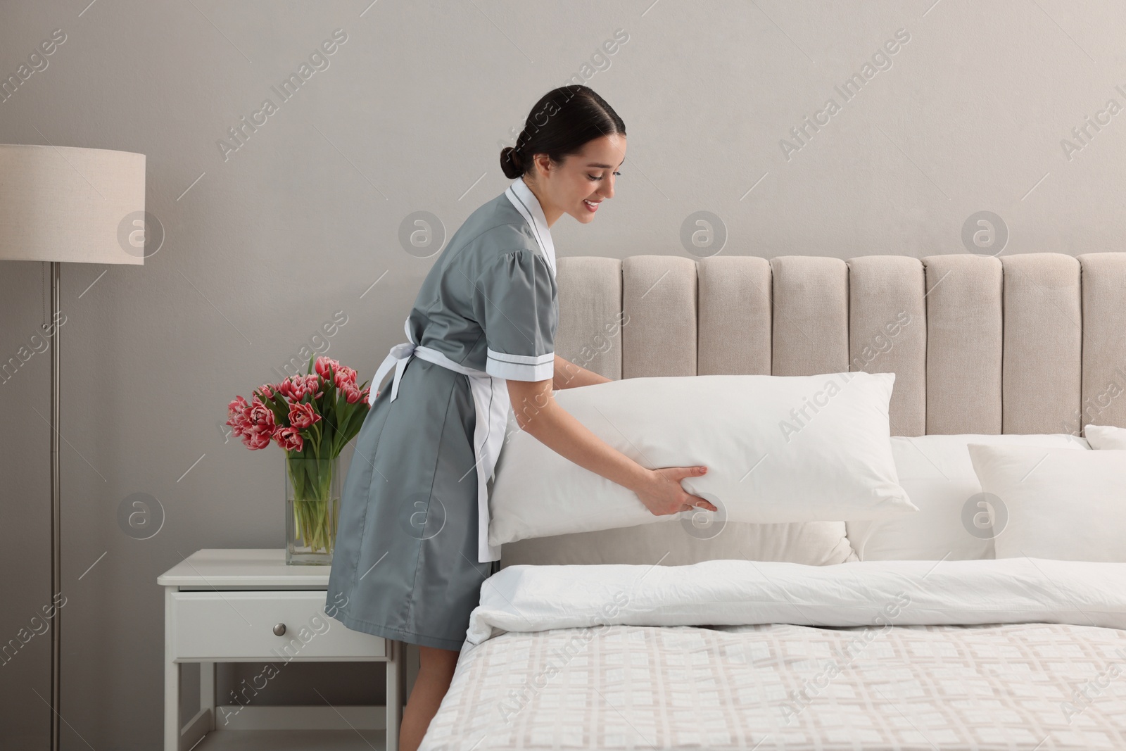 Photo of Professional chambermaid making bed in hotel room