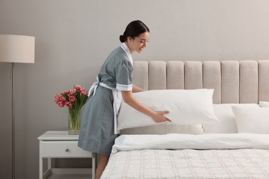 Photo of Professional chambermaid making bed in hotel room