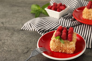 Photo of Piece of delicious Napoleon cake with fresh raspberries served on grey table, closeup. Space for text