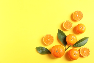 Photo of Fresh tangerines and leaves on color background, flat lay with space for text. Citrus fruits