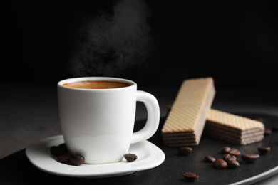 Delicious coffee and wafers on slate board, closeup. Space for text