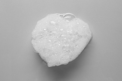 Drop of bath foam on light grey background, top view