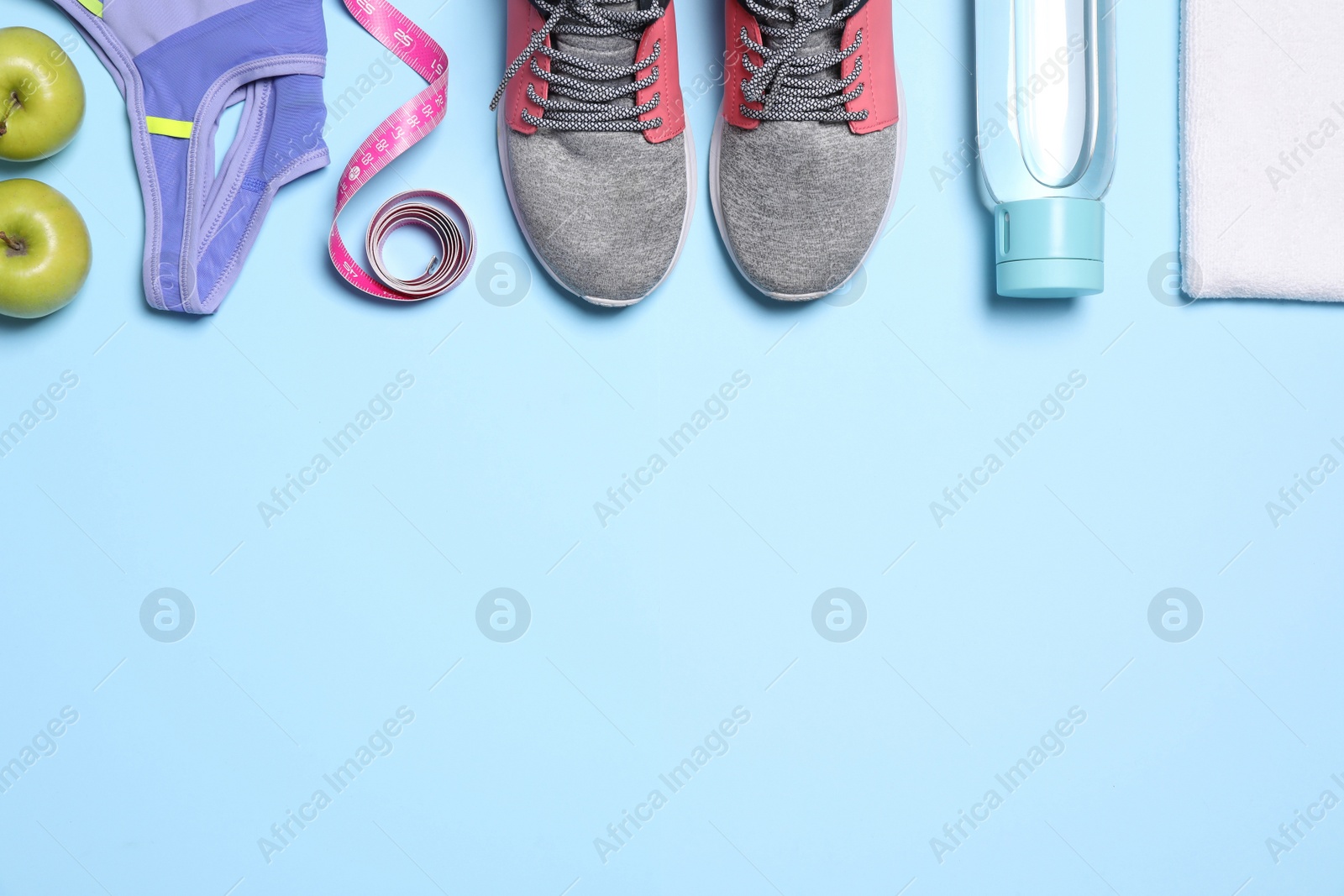 Photo of Flat lay composition with sneakers, measuring tape and sportswear on light blue background. Space for text