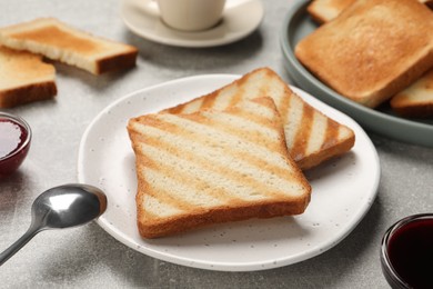 Photo of Slices of tasty toasted bread and jam on light grey table