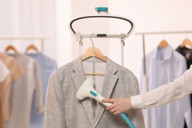 Woman steaming jacket on hanger in room, closeup