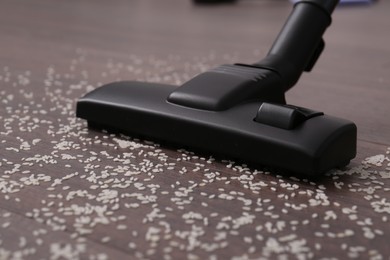 Vacuuming scattered rice from wooden floor, closeup