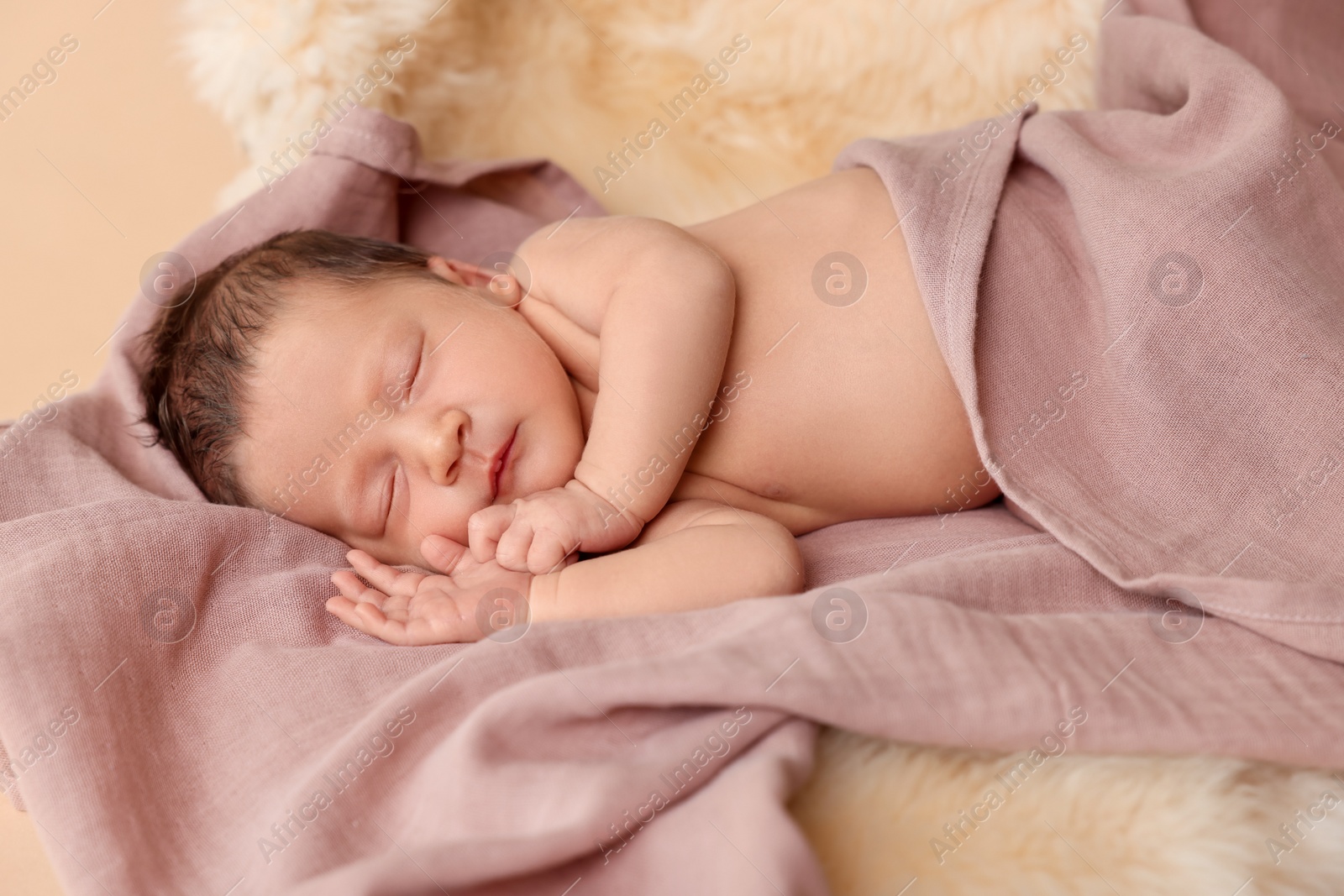 Photo of Adorable newborn baby sleeping on faux fur against beige background