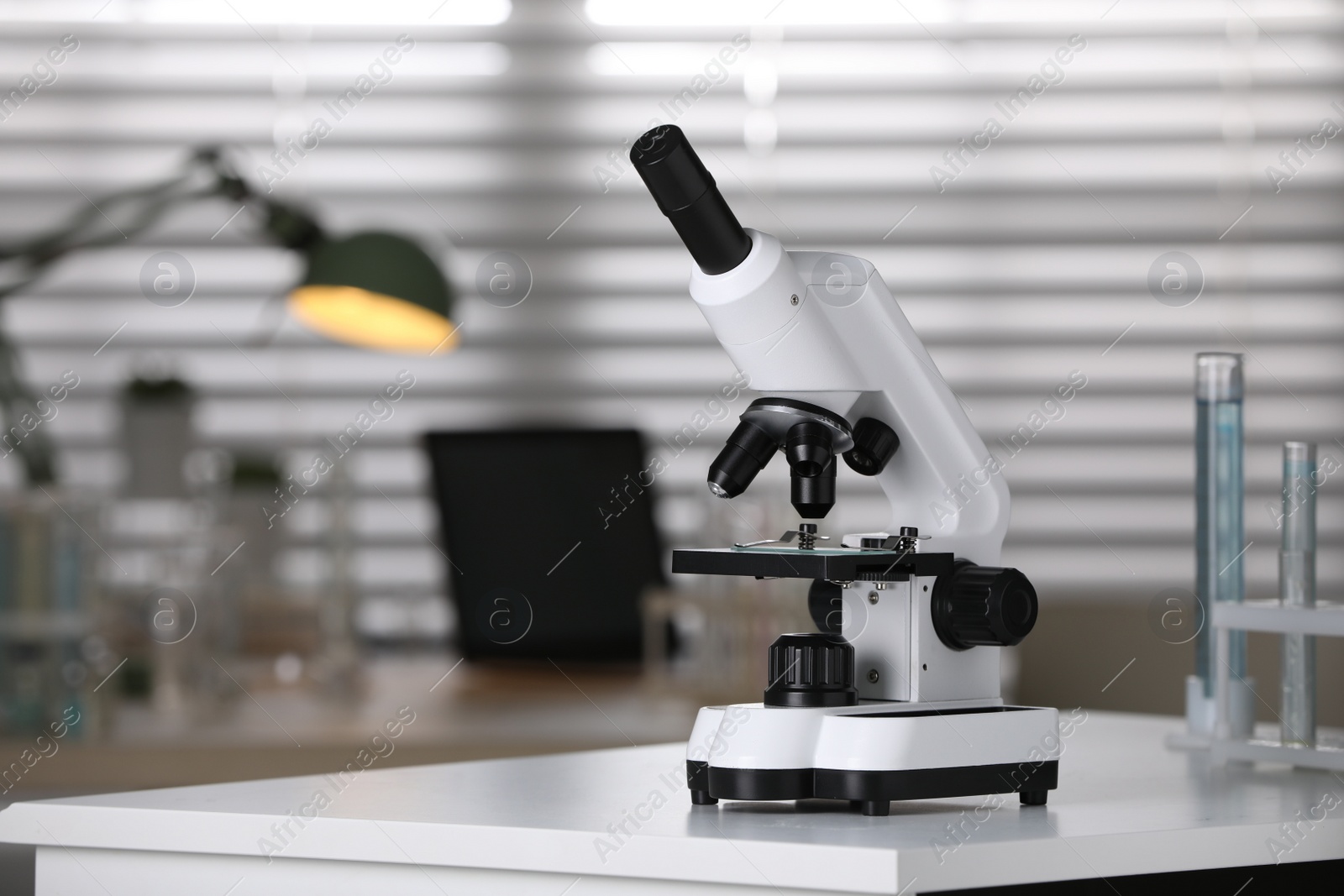 Photo of Modern medical microscope on white table in laboratory, space for text