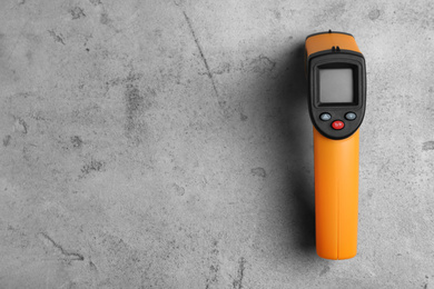 Modern non-contact infrared thermometer on light grey stone background, top view. Space for text