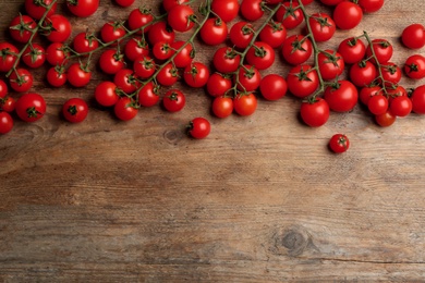 Fresh ripe cherry tomatoes on wooden table, flat lay. Space for text