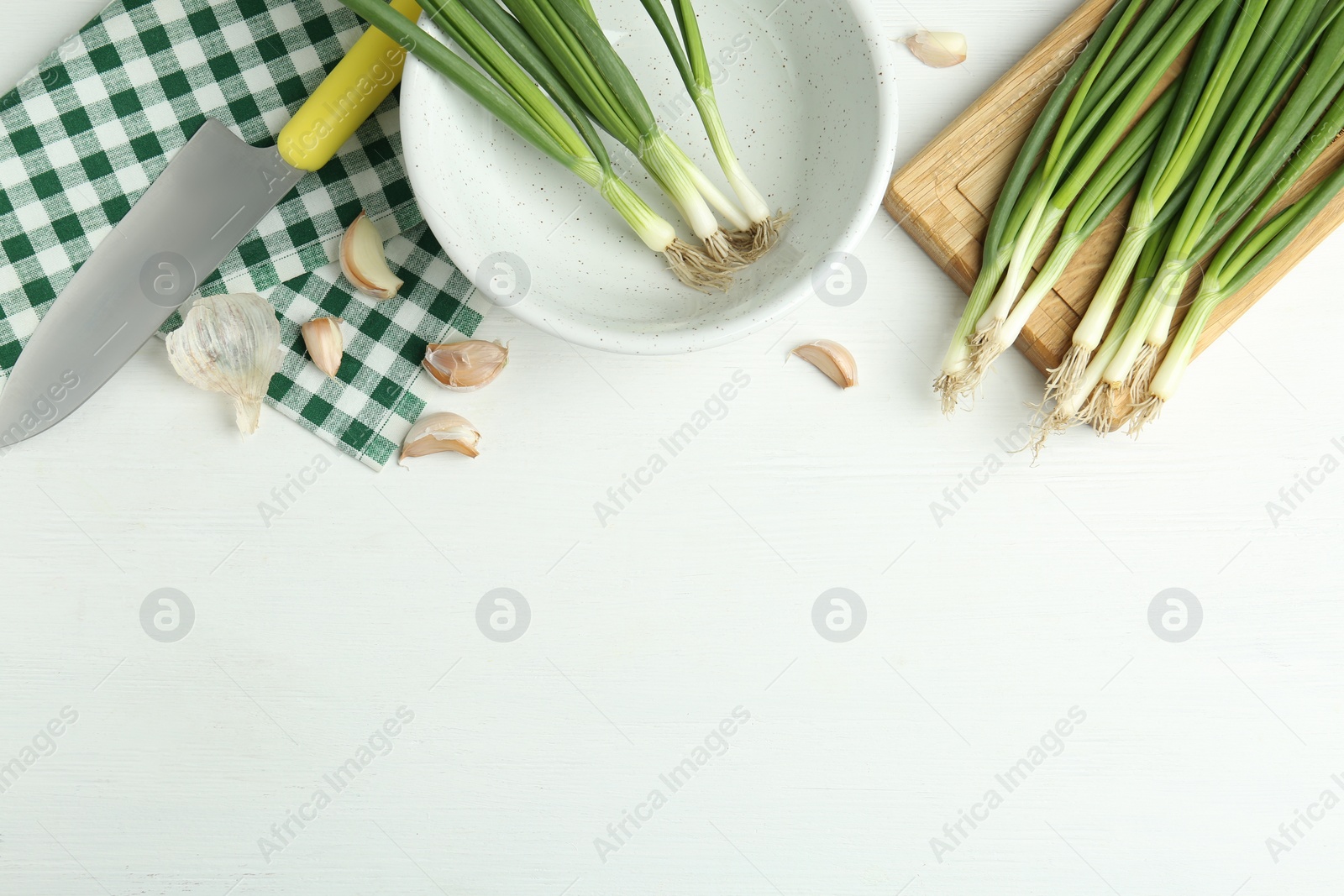 Photo of Flat lay composition with fresh green spring onions and garlic cloves on white wooden table. Space for text