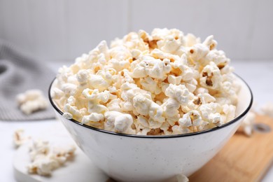 Photo of Bowl of tasty popcorn on white table, closeup