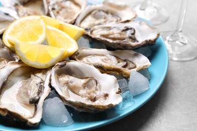 Fresh oysters with lemon on grey table, closeup