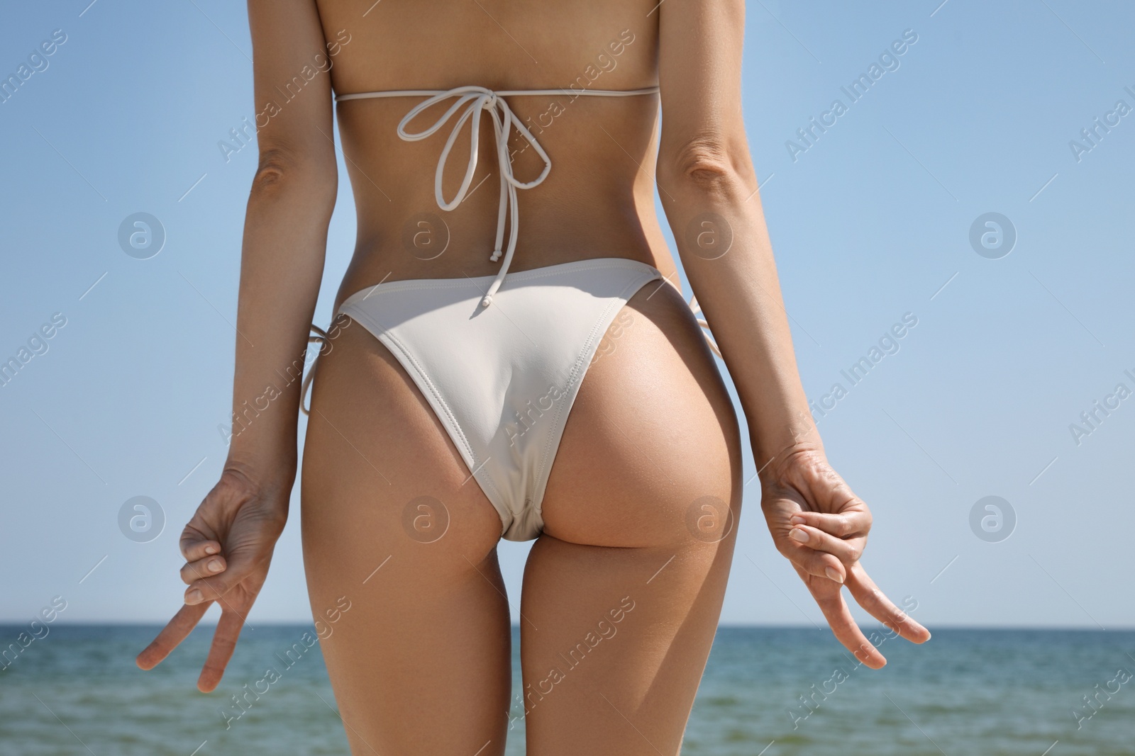 Photo of Woman with perfect body in bikini near sea, closeup. Back view