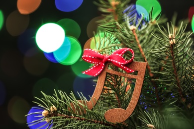 Photo of Fir tree with wooden music notes against blurred Christmas lights