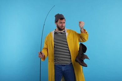 Fisherman with rod and old boot on light blue background