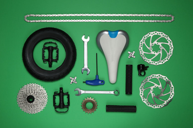 Photo of Set of different bicycle tools and parts on green background, flat lay