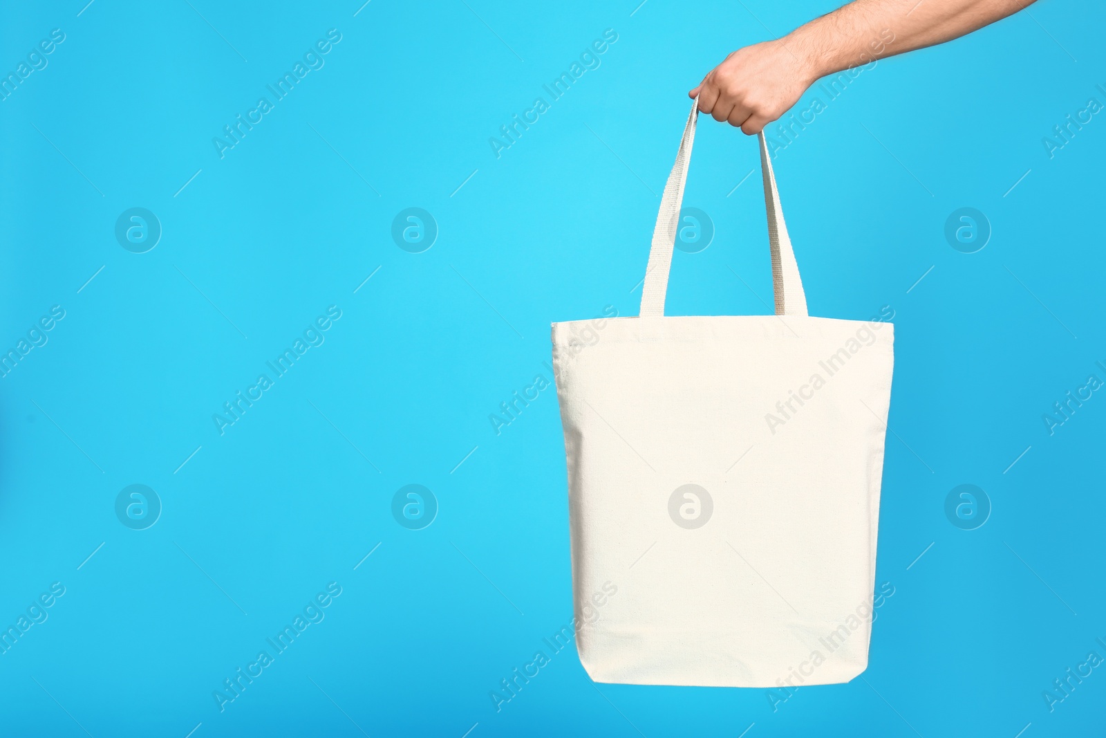 Photo of Young man with eco bag on blue background, closeup. Space for text